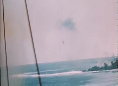PACIFIC - 1943: Landfall - Rigging frames a low island offshore Stock Footage 343931727