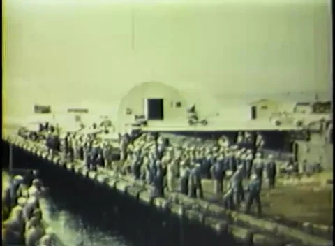 PACIFIC - 1945: Naval base - Ranks of men line the pier under a bright sky 库存影片 343931393