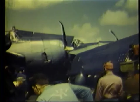 PACIFIC OCEAN - 1945: Deck servicing — a crewman works at an aircraft engine Vidéo 343120235
