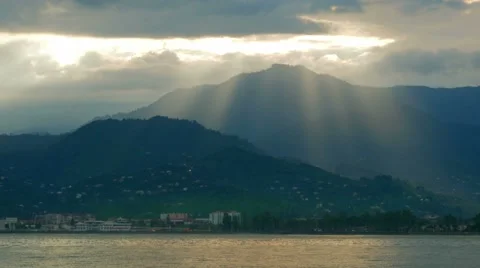 Pacific Ocean and the mountains behind. From the clouds make their way rays of Stock Footage 67609863