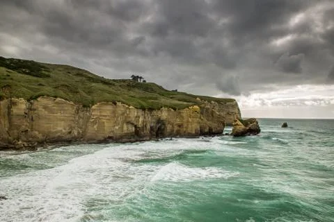 Pacific ocean meets sandy cliffs at Tunnel beach, Dunedin, New Zealand Stock Photos
