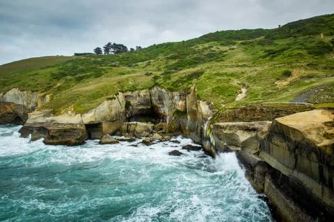 Pacific ocean meets sandy cliffs at Tunnel beach, Dunedin, New Zealand Stock Photos