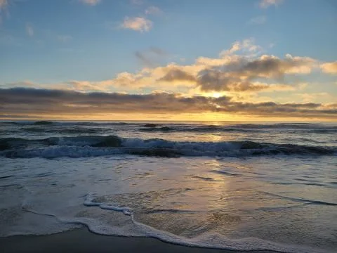 Pacific Ocean Sunset Waves Rolling Onto Sandy Beach with Golden Light Stock Photos