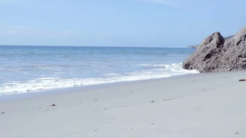 Pacific Ocean Waves on a Beach with a Large Rock Stock Footage 99307460