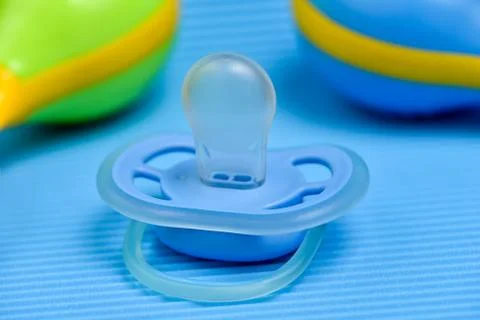 Pacifier on a blue background with a rattle. Stock Photos