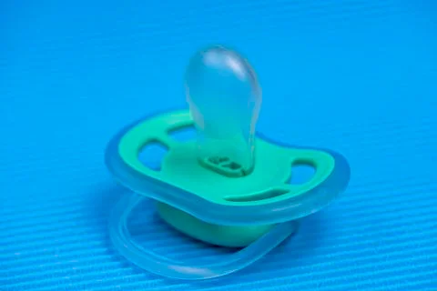 Pacifier on a blue background with a rattle. Stock Photos