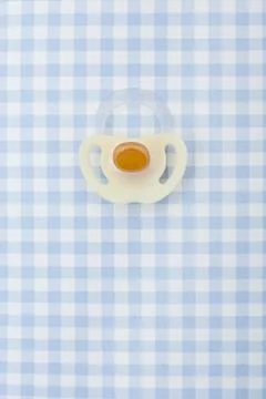 Pacifier on blue checker pattern Stockfoto's
