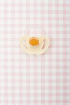 Pacifier on pink checker pattern Stockfoto's