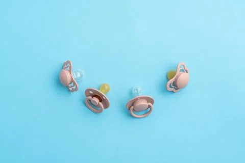 Pacifiers on blue background with copy space, top view of soothers, flat lay Stock Photos