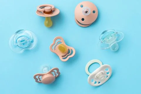 Pacifiers on blue background, newborn concept, top view of soothers, flat lay Stock Photos