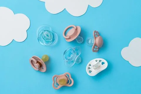 Pacifiers on blue background, newborn concept, top view of soothers, flat lay Stock Photos