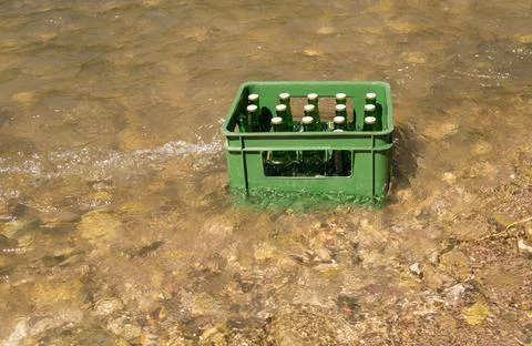 A pack of beer is cooling in the river Stock Photos