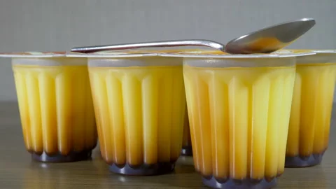 A pack of caramel dessert pots with a spoon on top. Video stock 142080309