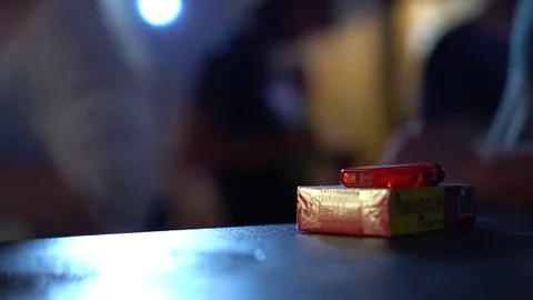 A pack of cigarettes and a lighter lies on the bar counter in a nightclub. Stock Footage 77559307
