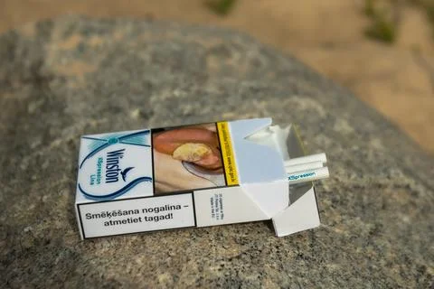 A pack of cigarettes was found on a stone on the seashore. Cigarettes fell out Stock Photos