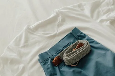 Pack of clothes on the bed with a white t-shirt blue short and clothe belt. Foto stock