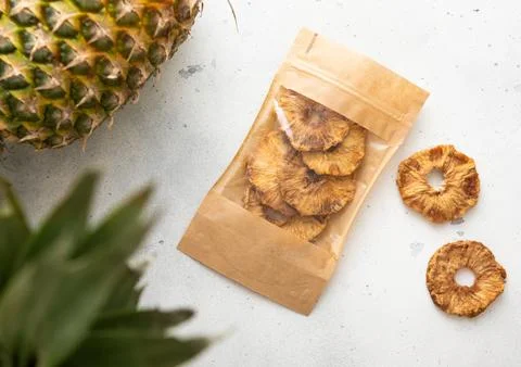 Pack of dried sweet pineapple circles on light background with raw pineapple Stock Photos