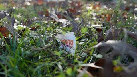 Pack of Dunkin Donuts sugar left as waste on a grassy field. Foto stock