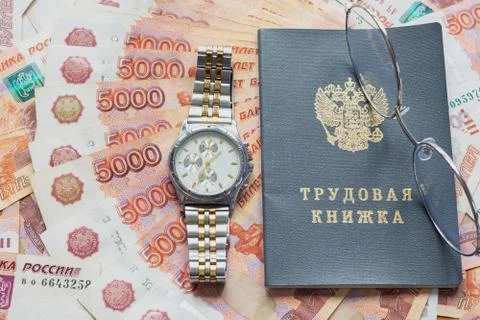 On a pack of five thousandth bills there is a work book, a watch and glasses Stock-Fotos