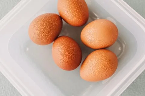 Pack of fresh eggs in plastic box on grey table cover. Stock Photos