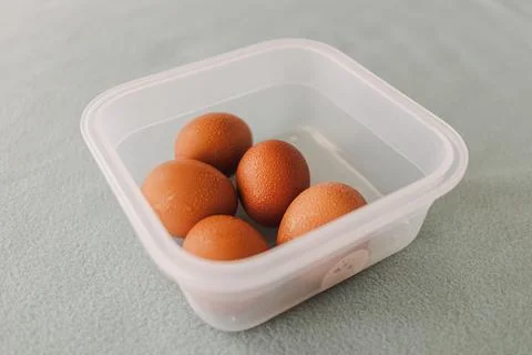 Pack of fresh eggs in plastic box on grey table cover. Stock Photos