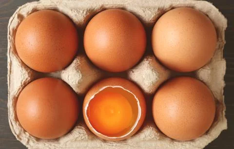 Pack of fresh organic eggs with an opened shell one in the carton box Stockfoto's