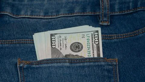 A pack of hundred-dollar bills in the back pocket of blue jeans, close-up. Stock Photos