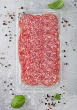 Pack of lassic salami slices with basil and pepper on light background. Foto stock