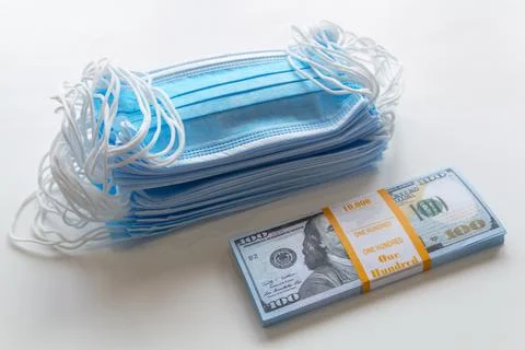 A pack of medical masks and a stack of 100 dollars bills as a symbol of highe Stock Photos