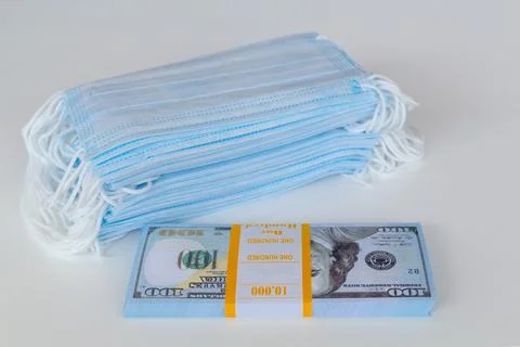 A pack of medical masks and a stack of 100 dollars bills as a symbol of highe Stock Photos