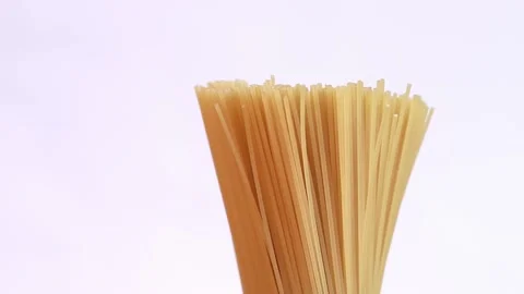 A pack of uncooked spaghetti rotates around on a light background Stock Footage 236101939