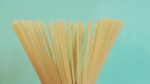 A pack of uncooked spaghetti rotates around on a blue background Stock Footage 236101942