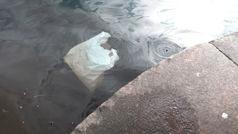 The package is floating in the water. the ecology is polluted. the dirty city Stockbeeldmateriaal 129092001