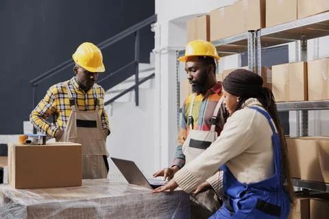 Package handlers packing parcel, checking orders list on laptop Stock Photos