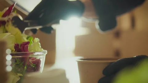 Package. A male worker dressed in work clothes packs fresh salads in disposa Stock Footage 266145035