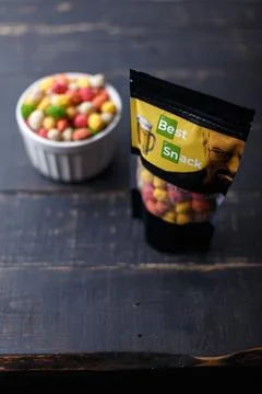 Package multiflavored peanuts in bright multicolored icing on black background Stock Photos
