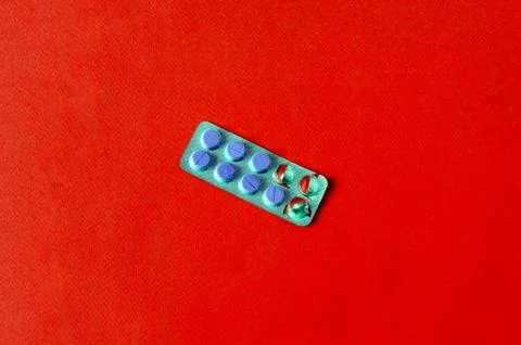 Package of opened purple tablets on a red background Stock Photos