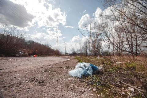A package of plastic garbage lies in the forest on a forest road, pollution o Stock Photos