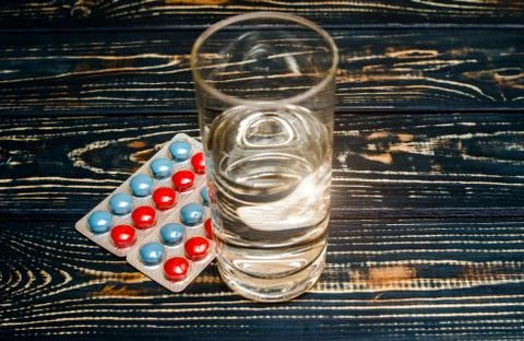 A package of red and blue tablets is placed on a brown background 写真素材