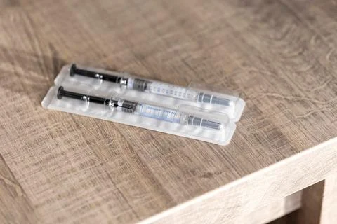 A package with two syringes in it lying on a wooden table. The drug injection Stock Photos