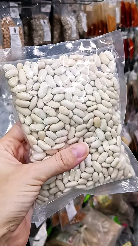 Package of white dry beans held in hand at grocery store Stock Footage 338031813