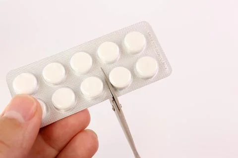 The package of white tablets is cut into doses. Medicine and health care. Stock Photos