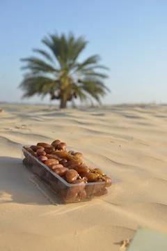 Packaged Dates on Desert Sand with Palm Tree in Background Stockfoto's