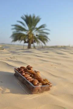 Packaged Dates on Desert Sand with Palm Tree in Background Stock Photos