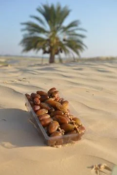Packaged Dates on Desert Sand with Palm Tree in Background 스톡 사진