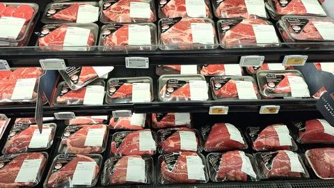 Packaged raw beef steaks displayed in supermarket refrigerated shelves Foto stock