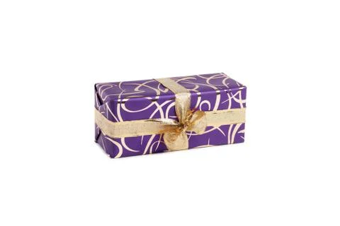 Packaged rectangular gift in purple packaging with gold bow and gold pattern on Stock Photos