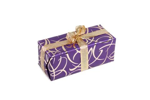 Packaged rectangular gift in purple packaging with gold bow and gold pattern on Stock Photos