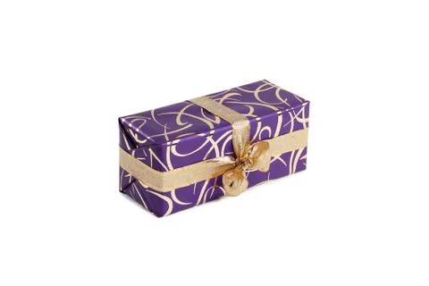 Packaged rectangular gift in purple packaging with gold bow and gold pattern on Stock Photos