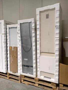 Packaged refrigerators in multiple sizes arranged neatly on pallets in ware.. Stock Photos